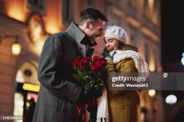 man giving his amazed girlfriend bunch of red roses on valentine's day - red couple stockfoto's en -beelden