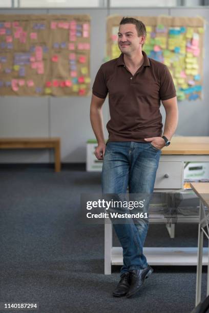 smiling businessman standing in office - brown jeans ストックフォトと画像