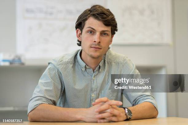 portrait of businessman sitting at desk in office - froncer les sourcils photos et images de collection