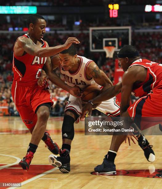 Derrick Rose of the Chicago Bulls drives between Jeff Teague and Joe Johnson of the Atlanta Hawks in Game Five of the Eastern Conference Semifinals...