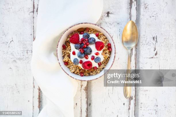 bowl of muesli with greek yogurt, popped quinoa, raspberries, blueberries and pomegranate seed - cereal bowl stockfoto's en -beelden