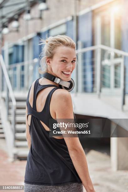 portrait of smiling young woman with headphones in front of gym - workout motivation stock pictures, royalty-free photos & images