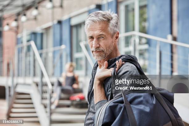portrait of mature man with sports bag in front of gym - carrying sports bag foto e immagini stock