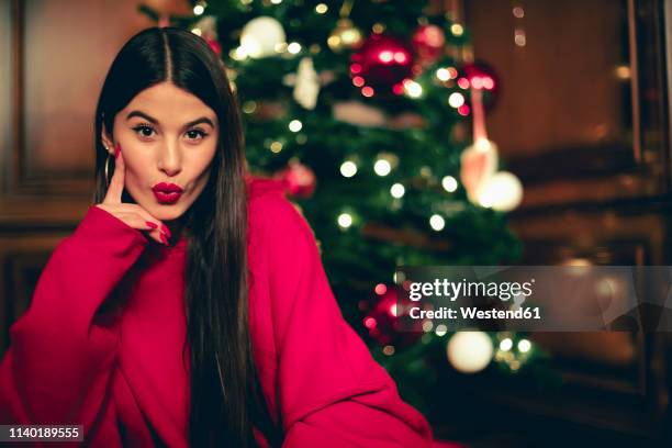 portrait of teenage girl with christmas tree in the background pouting mouth - red lipstick kiss stock pictures, royalty-free photos & images