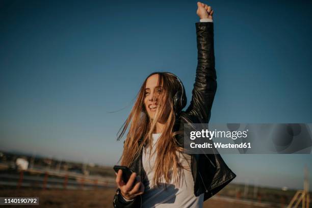 happy young woman listening music with headphones outdoors - smartphone musik stock-fotos und bilder