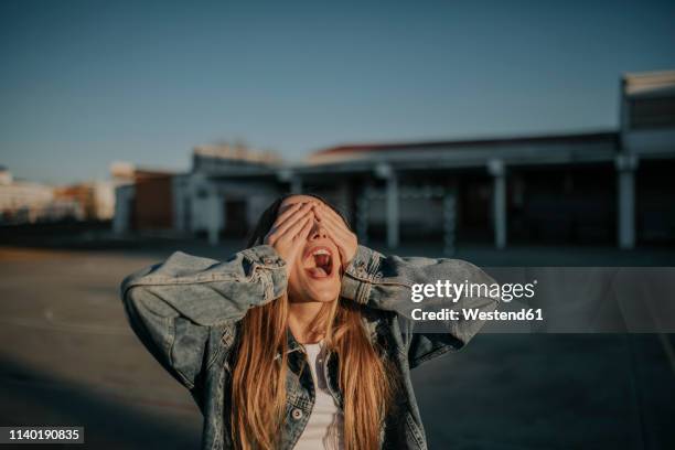 cheerful young woman covering her eyes outdoors - guess who stock pictures, royalty-free photos & images