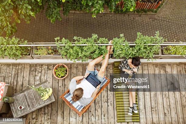 young couple relaxing on their balcony in summer, man using tablet - tablet paar sommer stock-fotos und bilder