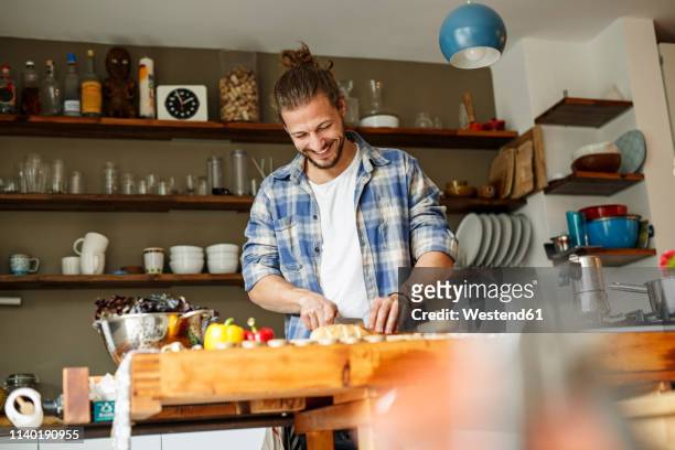 young man preparing food at home, slicing bread - junge männer stock-fotos und bilder