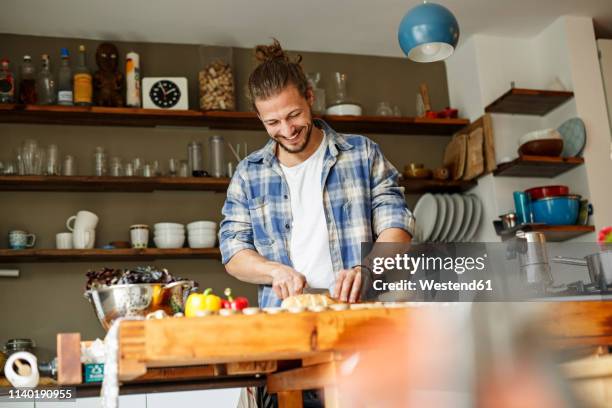 young man preparing food at home, slicing bread - homme cuisine photos et images de collection