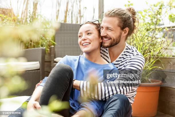 young couple relaxing on their balcony,  embracing - couple balcony stock pictures, royalty-free photos & images