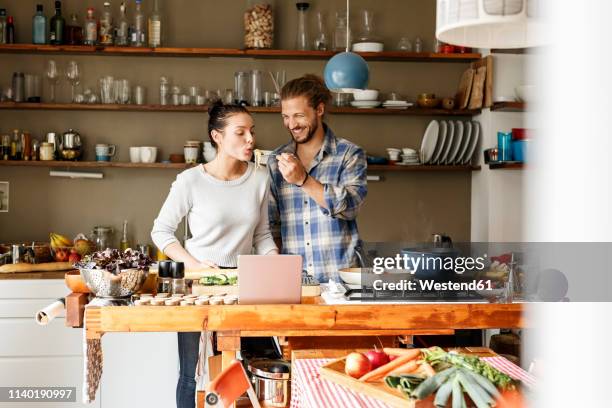 young couple preparing spaghetti together, using online recipe - cuisiner photos et images de collection