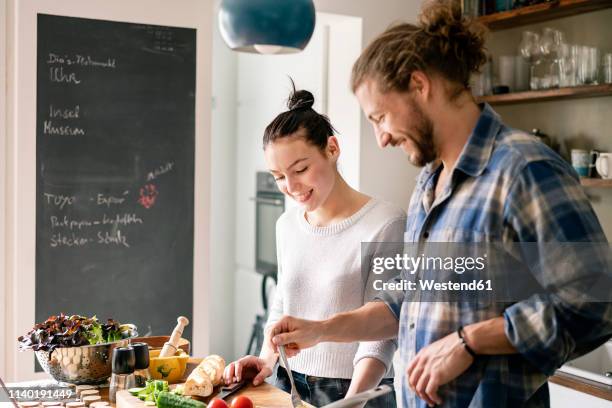 young couple preparing food together, tasting spaghetti - kochen stock-fotos und bilder