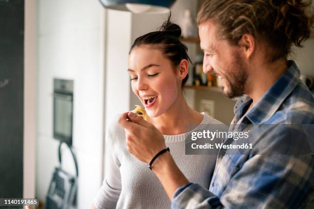 young couple preparing food together, tasting spaghetti - küche probieren stock-fotos und bilder
