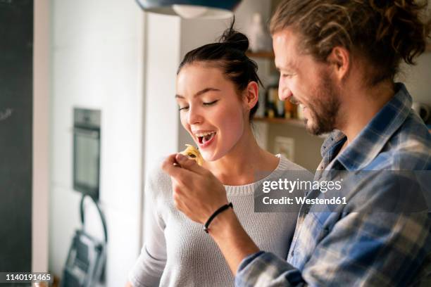 young couple preparing food together, tasting spaghetti - couple eating foto e immagini stock