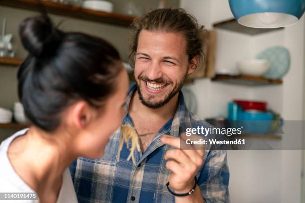 young couple preparing food together, tasting spaghetti - couple cooking photos et images de collection