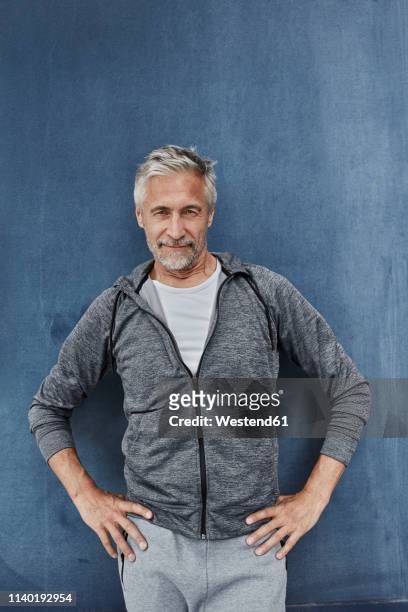 portrait of mature man standing in front of gym - sport blue background stock-fotos und bilder