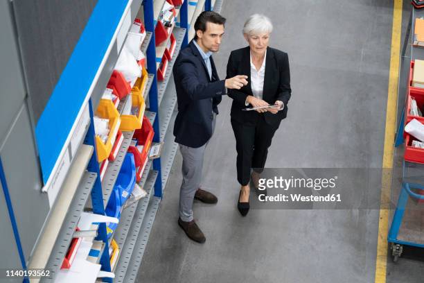businessman and senior businesswoman with tablet in a factory - successor stockfoto's en -beelden