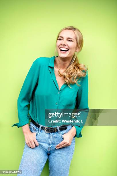 portrait of a cheerful young woman, against green background - colour background woman stock-fotos und bilder