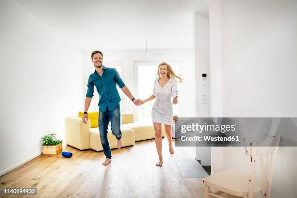 happy family moving into their new home, parents running hand in hand - woman home run stock pictures, royalty-free photos & images