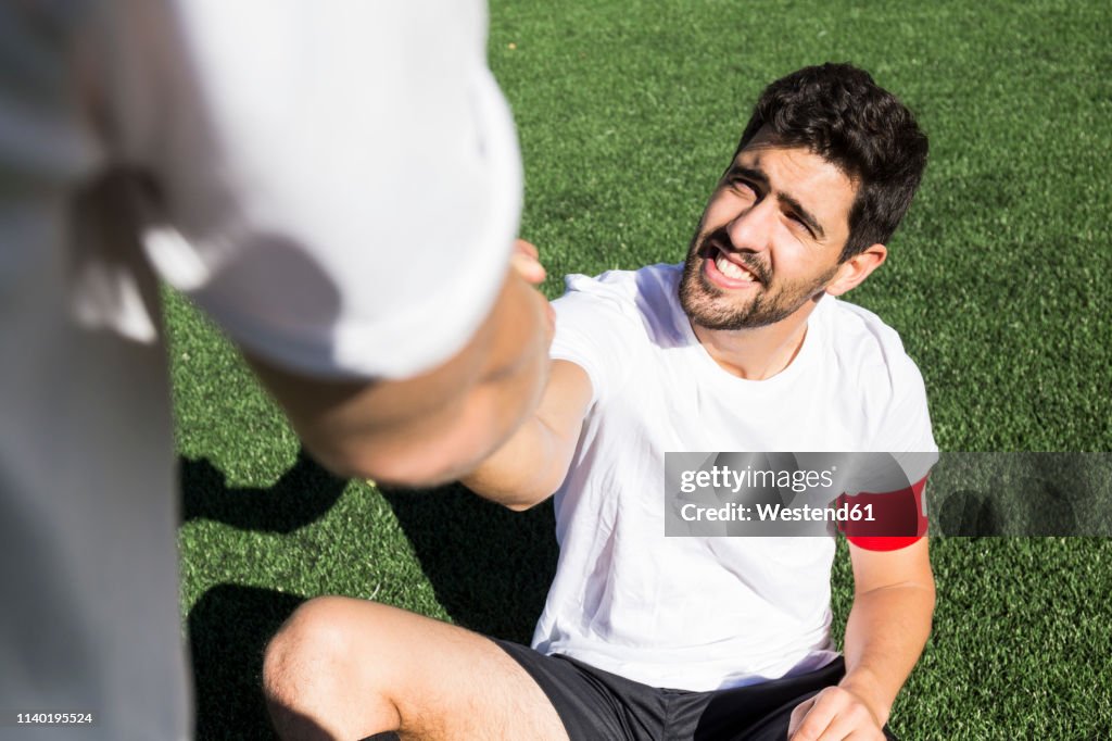 Football player helping an injured player during a match