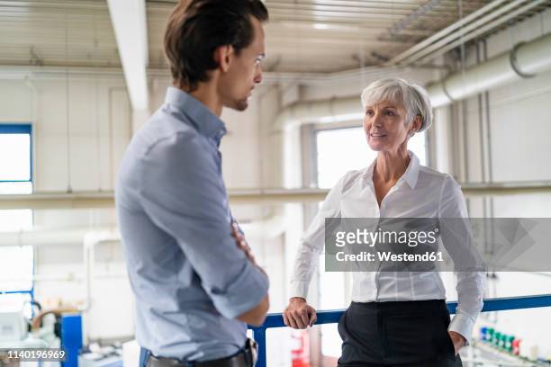 businessman and senior businesswoman talking in a factory - successor stockfoto's en -beelden