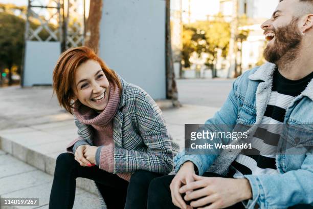 happy couple sitting outdoors laughing - city 2 fotografías e imágenes de stock