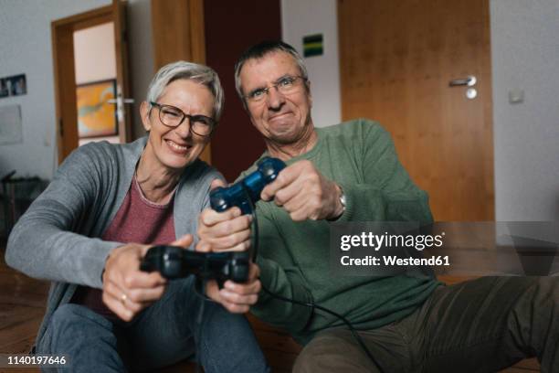 happy senior couple playing video game at home - couple de vieux drole photos et images de collection