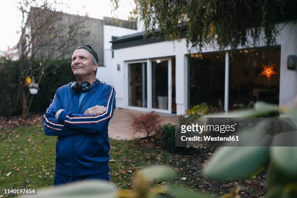 happy sportive senior man in tracksuit standing in garden - cooler opa stock-fotos und bilder