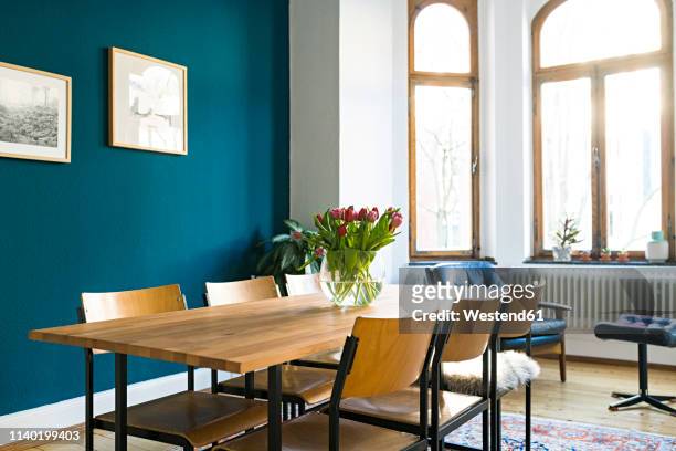 wooden table and chairs with large window front in modern living room in stylish apartment - eetkamer stockfoto's en -beelden