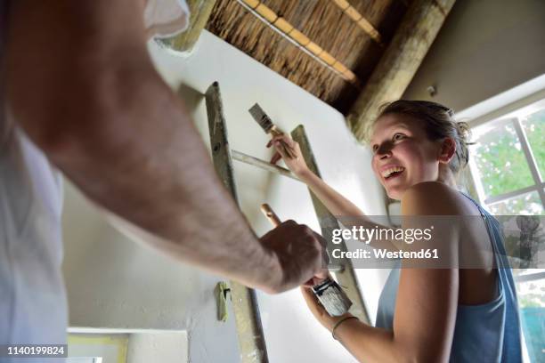 happy young couple renovating their home painting the wall together - couple painting stock-fotos und bilder