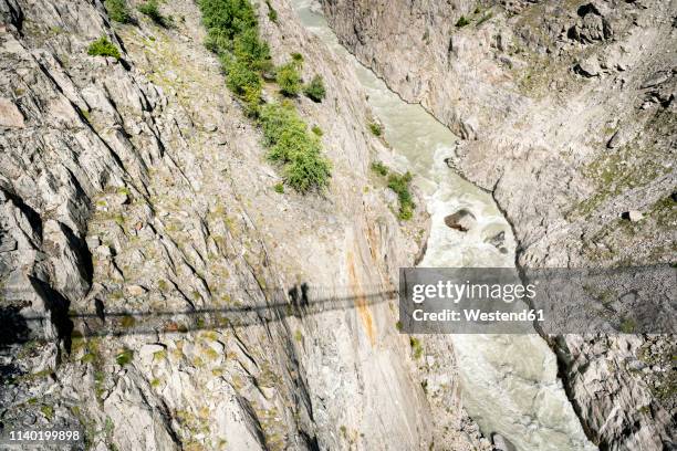 switzerland, valais, shadows of two people on a swinging bridge above a gorge - abyss stock-fotos und bilder