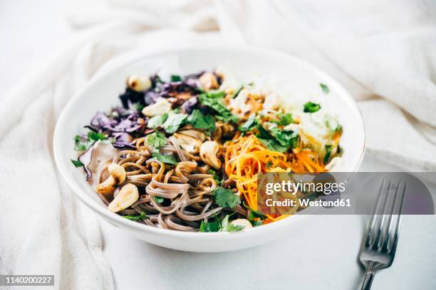 bowl of buckwheat noodle salad with raw vegetables, roasted cashews,  coriander and spicy dressing - soba stock pictures, royalty-free photos & images