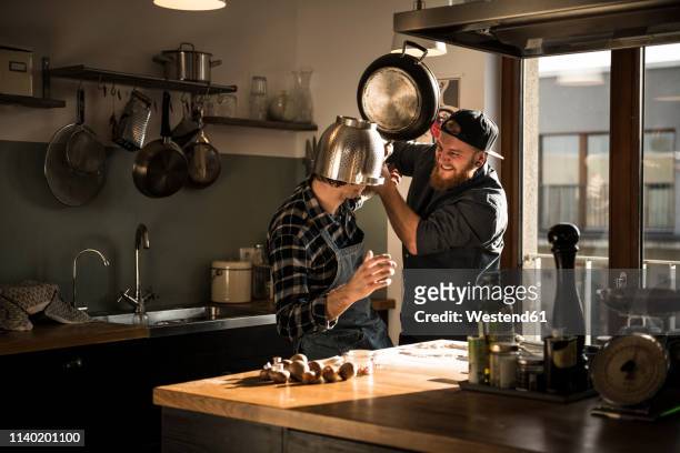 friends having a duel with a colander and a pan in the kitchen - friend enemy stock pictures, royalty-free photos & images