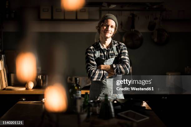 proud hobby chef standing in his kitchen, with arms crossed - hipster in a kitchen stockfoto's en -beelden