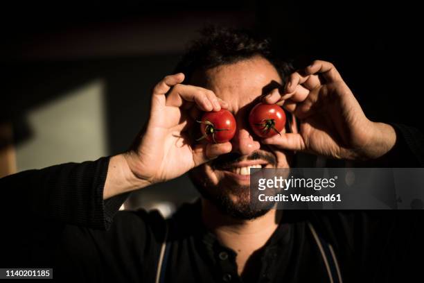 man covering his eyes with tomatoes - funny vegetable stockfoto's en -beelden
