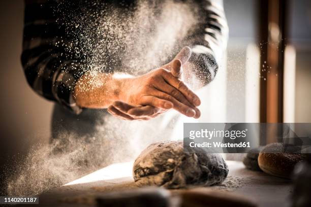 man preparing black burger buns in kitchen - baking foto e immagini stock
