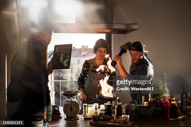 friends flambeing food in a pan, producing a big flame, while friend is filming - passion bildbanksfoton och bilder