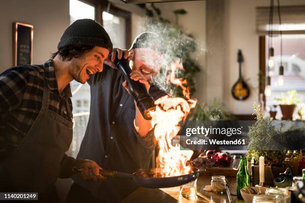 friends flambeing food in a pan, producing a big flame - cooking together stockfoto's en -beelden