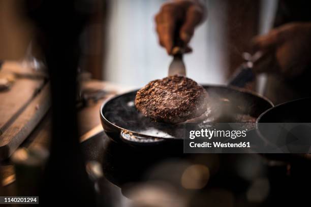 man frying beef patties in a pan - preparación de alimentos fotografías e imágenes de stock