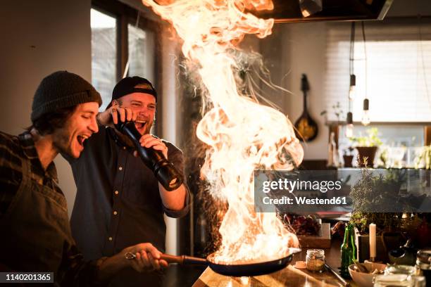 friends flambeing food in a pan, producing a big flame - passion stock pictures, royalty-free photos & images