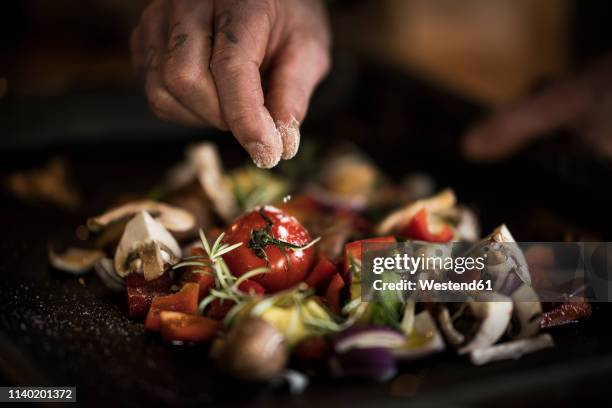 hand seasoning vegetables ona a baking tray - salt seasoning stock pictures, royalty-free photos & images