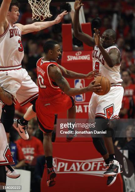 Jeff Teague of the Atlanta Hawks passes the ball between Omer Asik and Loul Deng of the Chicago Bulls in Game Five of the Eastern Conference...