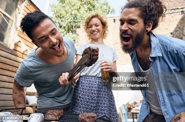 friends having a barbecue n the backyard, preparing meat on a grill - social bite stock pictures, royalty-free photos & images