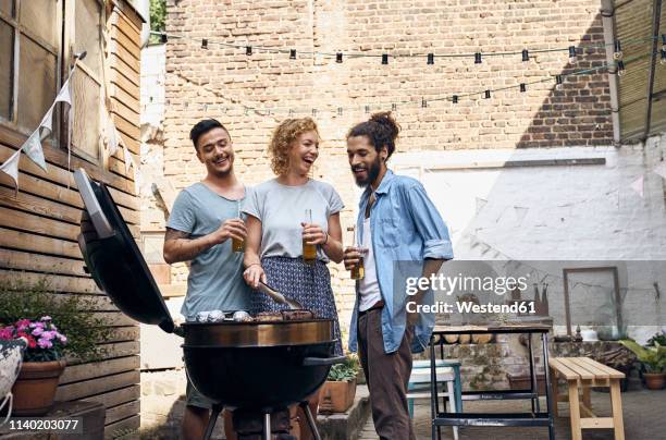 friends having a barbecue n the backyard, preparing meat on a grill - grill party stockfoto's en -beelden