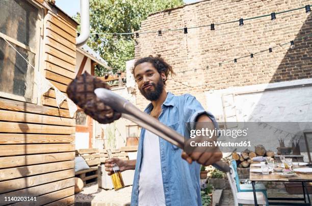 young man preparing meat on a barbecue grill in a backyard - barbecue man stock pictures, royalty-free photos & images