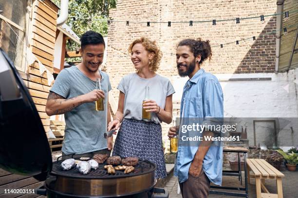 friends having a barbecue n the backyard, preparing meat on a grill - asian person bbq stock-fotos und bilder