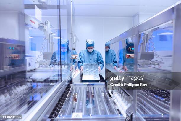 male worker inspecting flex circuit in flexible electronics factory clean room - clean suit fotografías e imágenes de stock