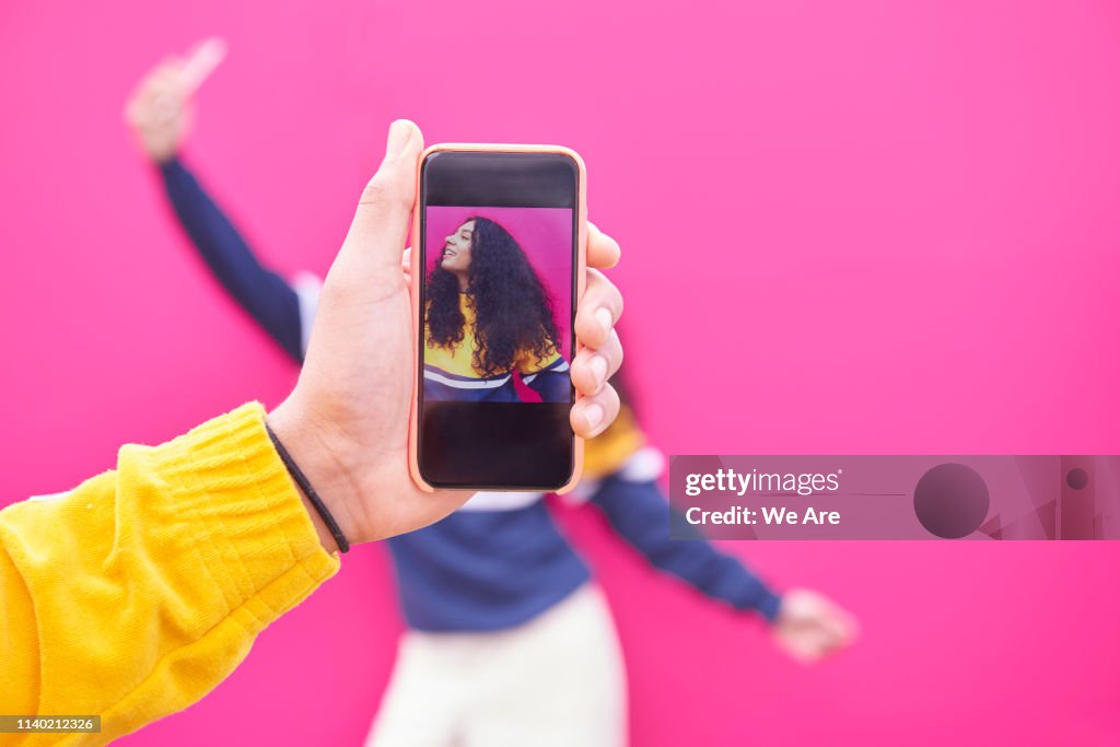 Man taking photo of friend on smartphone