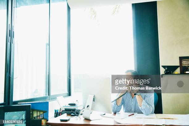 Businessman on phone while working on computer in office