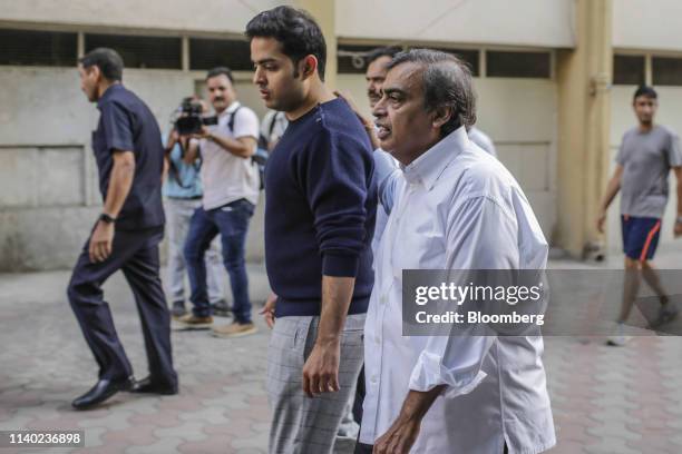 Mukesh Ambani, chairman and managing director of Reliance Industries Ltd., right, his son Akash Ambani, depart a polling station during the fourth...